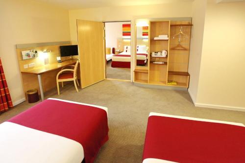 a hotel room with a bed and a desk and a bedroom at Holiday Inn Express Birmingham Redditch by IHG in Redditch