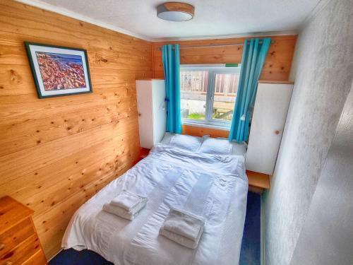 a small bedroom with a bed and a window at Caswell Beach Chalet 70 located in Gower Peninsula in Swansea