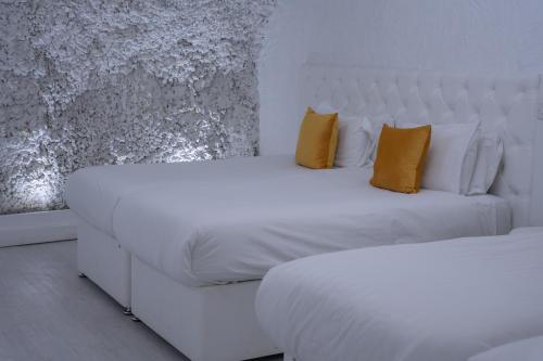 a bedroom with two beds with white sheets and yellow pillows at The Dixie Dean Hotel in Liverpool
