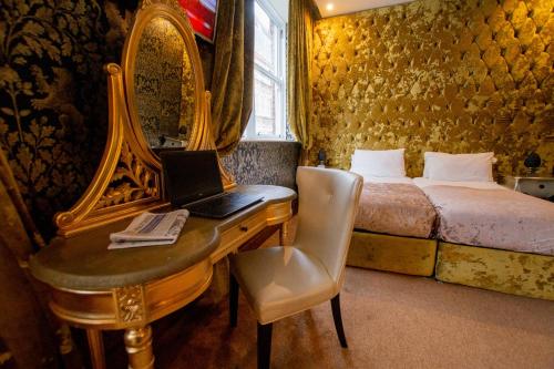 a bedroom with a bed and a desk with a laptop at The Dixie Dean Hotel in Liverpool