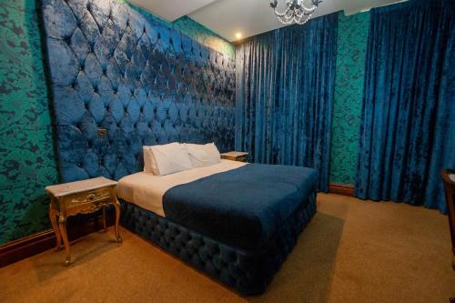 a bedroom with a bed and a blue wall at The Dixie Dean Hotel in Liverpool