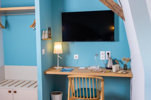 Zimmer mit einem Schreibtisch und einem TV an einer blauen Wand in der Unterkunft Cueillette in Altillac