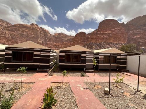 a couple of buildings in front of some mountains at Wadi Rum Oryx Hostel & Tours in Wadi Rum