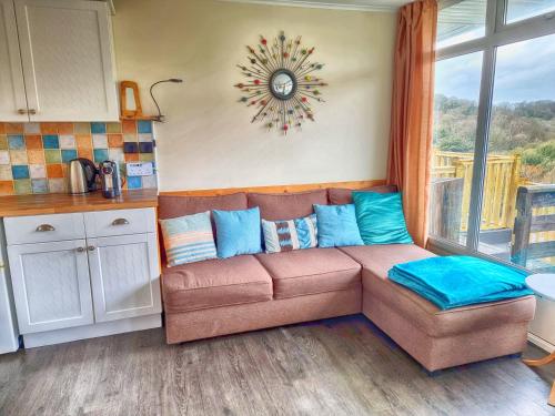 a brown couch in a kitchen with a clock on the wall at Caswell Beach Chalet 70 located in Gower Peninsula in Swansea