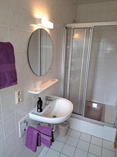 a bathroom with a sink and a shower with purple towels at Moselpension Gwosch in Bruttig-Fankel