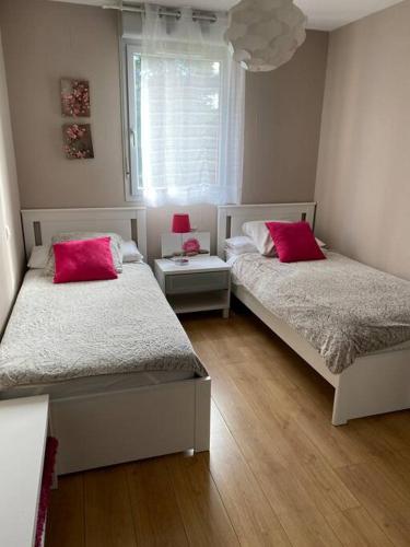 - une chambre avec 2 lits dotés d'oreillers rouges et d'une fenêtre dans l'établissement Calme & Confort - proche Cité de l'Espace, à Toulouse