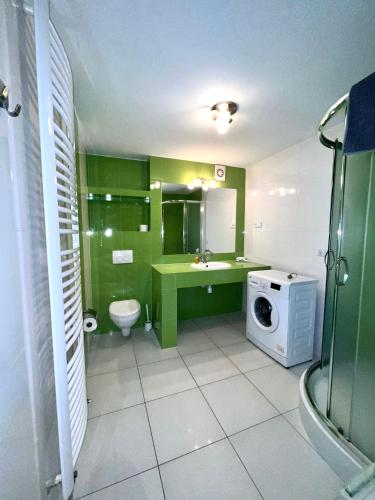 La salle de bains est pourvue d'armoires vertes et d'un lave-linge. dans l'établissement Apartamenty Wałowa 7a - ap. Słoneczny, à Łańcut