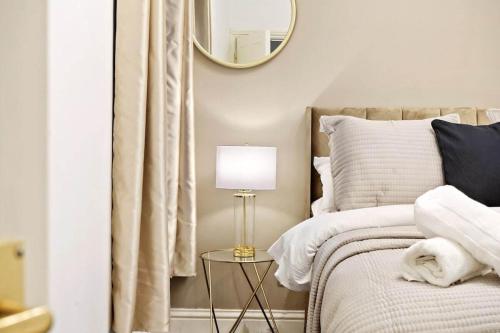 a bedroom with a bed with a lamp and a mirror at Stylish 2BR Luxury Retreat with 65" Smart TV in Kent