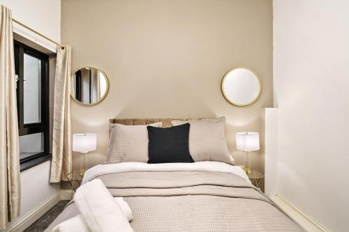 Stylish 2BR Luxury Retreat with 65" Smart TV في Kent: غرفة نوم مع سرير ومرآتين على الحائط