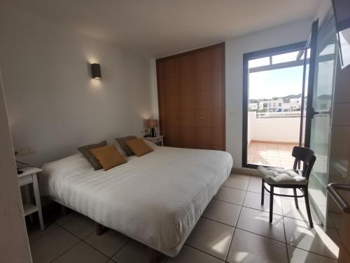 um quarto com uma cama, uma cadeira e uma janela em Casa Apartamento Mojacar Macenashome em Mojácar