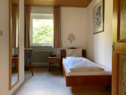 a small bedroom with a bed and a window at Alpenhotel Sonneck - mit Bergbahnticket in Bad Hindelang