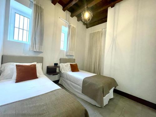 a bedroom with two beds and two windows at Eva Recommends Triana in Seville