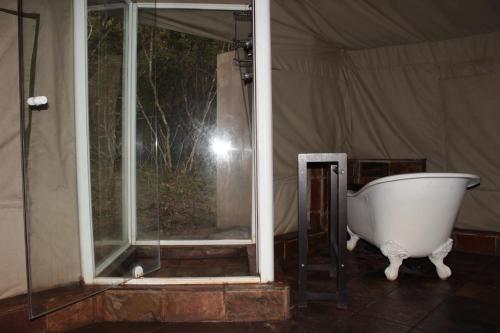 Inkwenkwezi Private Game Reserve في شنتسا: وجود حوض استحمام الجلوس بجانب نافذة في خيمة