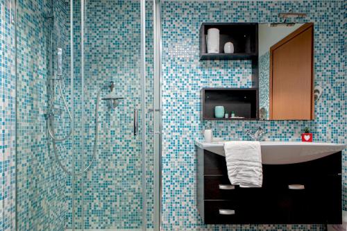 baño con lavabo y ducha con azulejos azules en Sea Breeze Loft, en Livorno