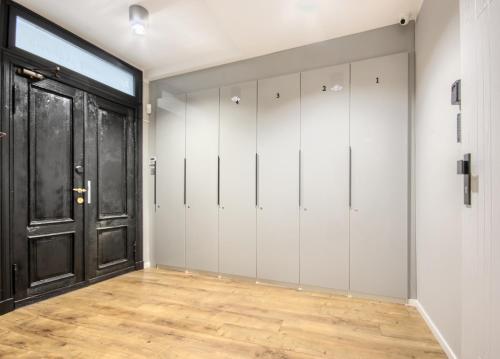 een kleedkamer met witte kluisjes en een zwarte deur bij Studio Bueno 5.1. - ACCO RENT in Gdańsk