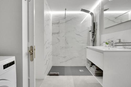 a white bathroom with a shower and a sink at 7even in Corralejo