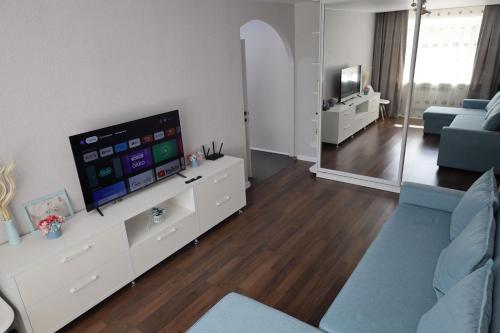 een woonkamer met een tv en een blauwe bank bij Люкс в центре Караганды in Karagandy