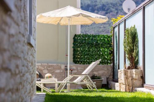 an umbrella and chairs in the grass on a patio at Sokaki Villas, rustic ambience, By ThinkVilla in Khromonastírion