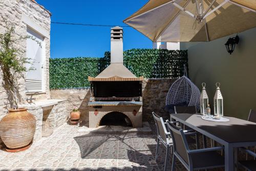 a outdoor patio with a fireplace and a table with an umbrella at Sokaki Villas, rustic ambience, By ThinkVilla in Khromonastírion
