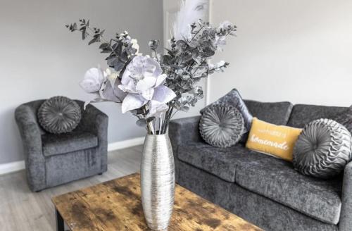 a vase with flowers on a table in a living room at Luxury 3 bedroomed home in Kettering