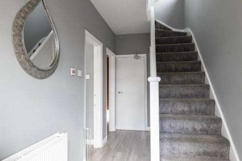 a hallway with a staircase with a mirror and a stair case at Luxury 3 bedroomed home in Kettering