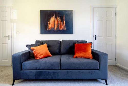 a blue couch with two orange pillows in a living room at Newly Refurbished Homely 4BR in Sherwood in Nottingham