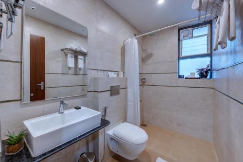 a bathroom with a sink and a toilet and a window at De Garland Palolem - AM Hotel Kollection in Palolem