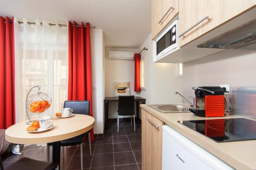 a kitchen with a table and a small kitchen with red curtains at Villa Serafina Apartements in Nice