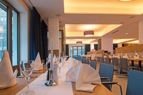 a restaurant with a long table with chairs and glasses at Bayer 89 Vi Vadi Hotel in Munich