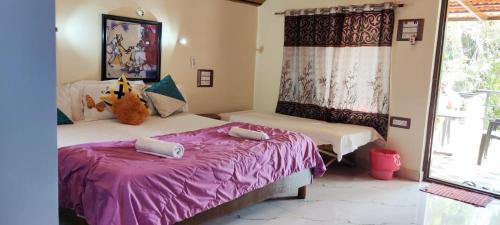 two beds in a room with purple sheets and a window at Shankar Homestay in Hampi