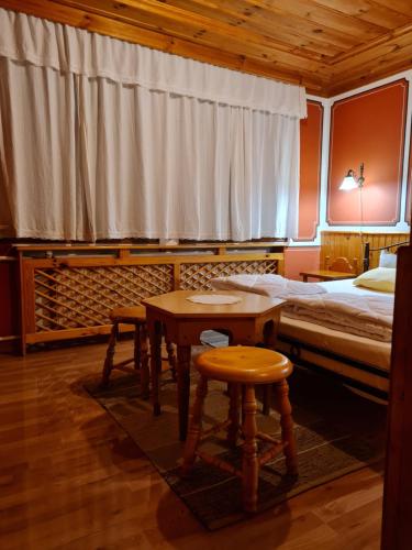 - une chambre avec un lit, une table et un tabouret dans l'établissement Астра къща за гости, à Koprivchtitsa