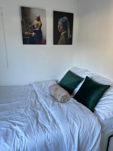 a bed with green pillows and two pictures on the wall at Chalet ‘De Sânkop’ in Makkum