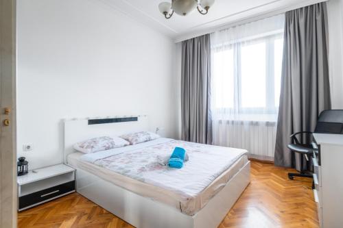 a white bedroom with a bed with a blue object on it at Vitosha Str 2BD White & Blue Apt in Sofia