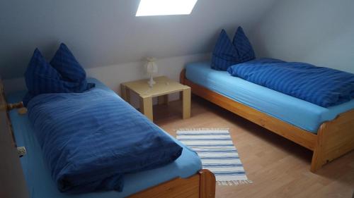 a bedroom with two beds with blue pillows and a table at *Engels - Ferienwohnungen in Visquard