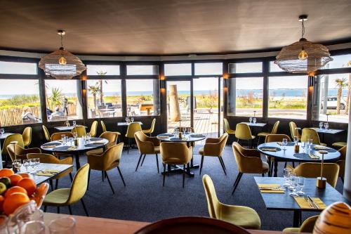 a restaurant with tables and chairs and windows at Hotel Castel Moor in Le Croisic