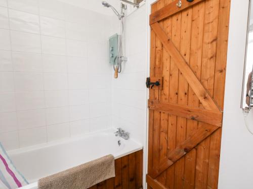 ein Badezimmer mit einer Holztür, einer Badewanne und einem Waschbecken in der Unterkunft Eweleaze in Dorchester