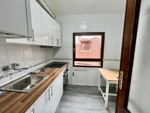 eine Küche mit weißen Schränken, einem Waschbecken und einem Fenster in der Unterkunft Centro Historico Valentin Palencia Vut 09/440 in Burgos