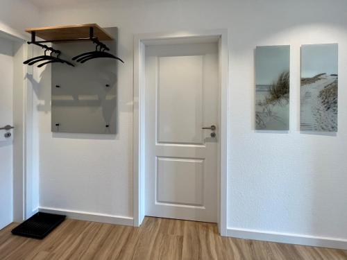 Zimmer mit weißer Tür und Holzboden in der Unterkunft DünePur in Norderney
