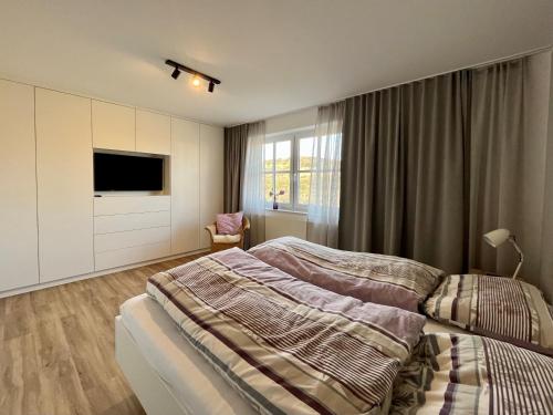 a bedroom with a bed and a flat screen tv at DünePur in Norderney