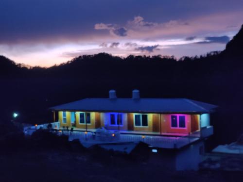 a house lit up at night with colorful lights at Himrab Chopta Resort in Chopta