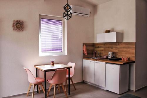 a small kitchen with a table and pink chairs at My place studio in Ohrid