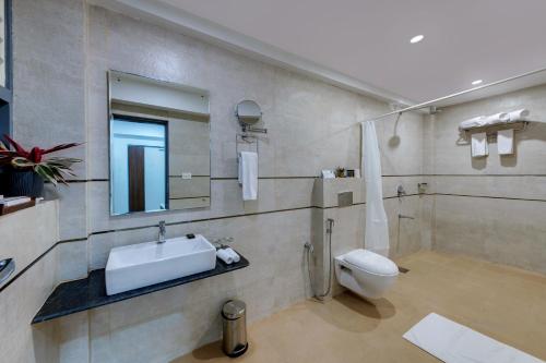 De Garland Palolem - AM Hotel Kollection في بالوليم: حمام مع حوض ومرحاض ومرآة