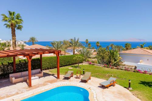 a swimming pool with a pergola and chairs and the ocean at Sharm and Charme at Sharm El Sheikh in Sharm El Sheikh