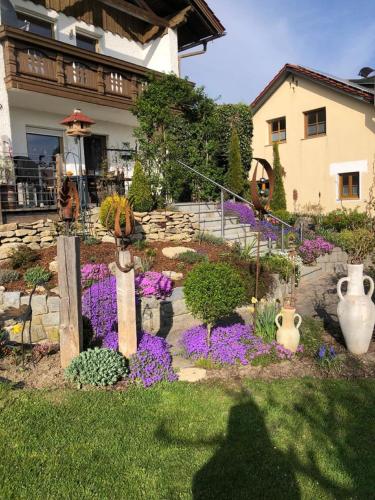 a garden with purple flowers in front of a house at Ferienwohnung Hinterberg in Fürstenstein