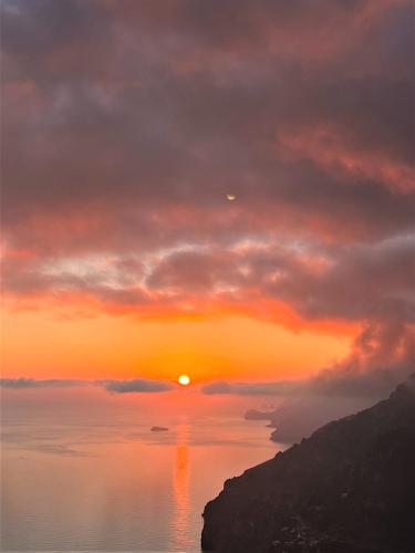 a sunset over a body of water with the sun setting at Colle dell'Ara in Positano