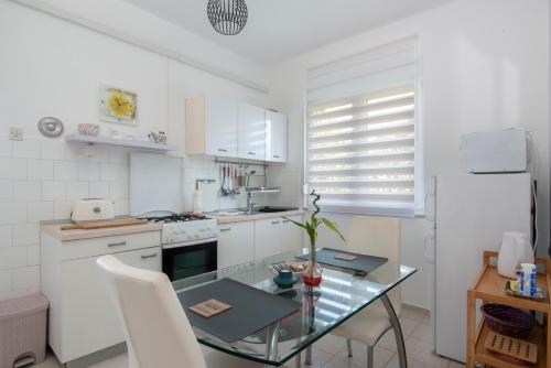 烏馬格的住宿－Seafront Apartment Jadri，厨房配有玻璃桌和白色家电