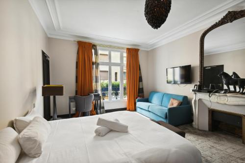 ein Schlafzimmer mit einem großen weißen Bett und einem blauen Sofa in der Unterkunft Le Paris Singulier in Paris