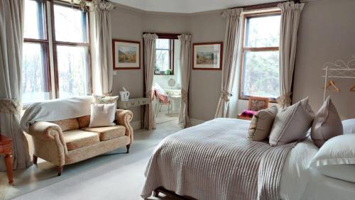 a bedroom with a bed and a chair and windows at Isla Bank House in Keith