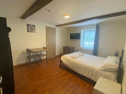 Un dormitorio con una cama y una mesa. en L'ANNEXE DE L'AMERIVIERE en Aubrives