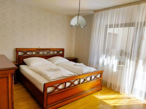 a bedroom with a wooden bed with white sheets and a window at Apartments im Taunus in Neu-Anspach